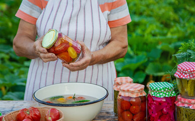 Senior woman preserving vegetables in jars. Selective focus.