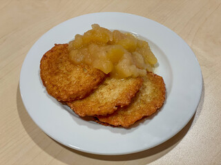 Crispy German potato pancakes Kartoffelpuffer served with homemade applesauce on a plate high angle view. Classic comfort food and popular winter specialty in Germany.