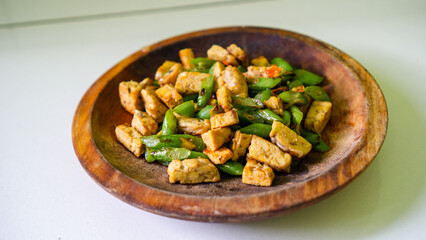 Stir-fried tofu and green beans in rustic wooden bowl