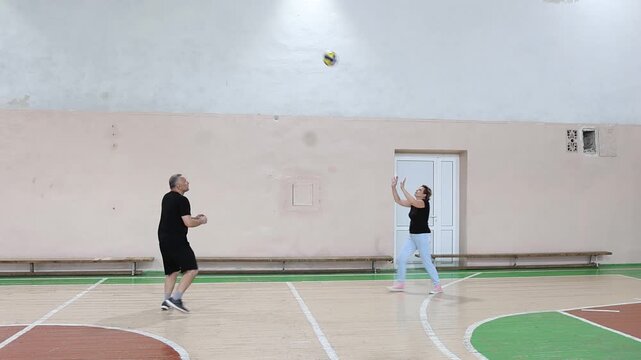 Woman and man playing volleyball in the gym
