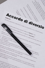 Accordo di divorzio in Italian or Marital Settlement Separation Divorce Agreement paper document with wedding rings on table, symbolizing divorce, prenuptial contract, prenup, breakup for Italy.