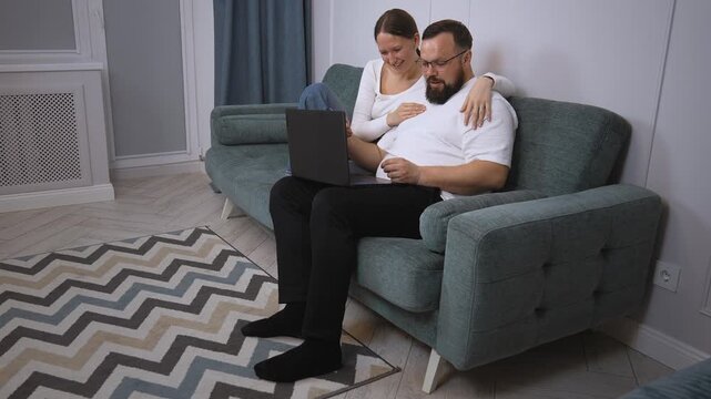 Young couple sitting on couch and using world wide web for home shopping and using credit card and laptop to shop online