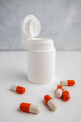 Medicine Capsules and Open Bottle on White Surface