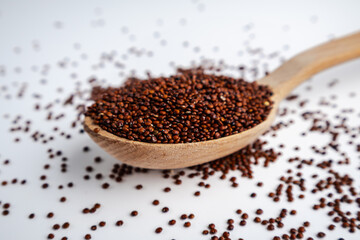Red Quinoa Seeds on a Wooden Spoon with Scattered Grains
