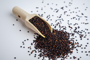 Black Quinoa Seeds with Wooden Scoop on White Background