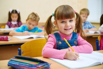 Smiling Girl Writing in Notebook During Class