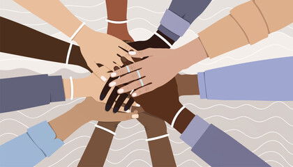 Diverse group of people stacking hands in a symbol of unity and teamwork against a neutral background with a flat lay composition.