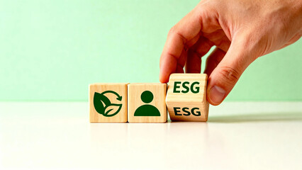 Hand placing wooden block with ESG text next to blocks featuring environmental and people icons