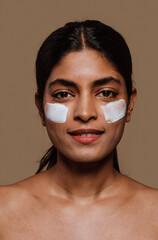  Young woman applying moisturizer on face