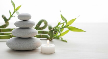 Fototapeta premium Zen stones stacked with candle and bamboo leaves for relaxation and meditation.