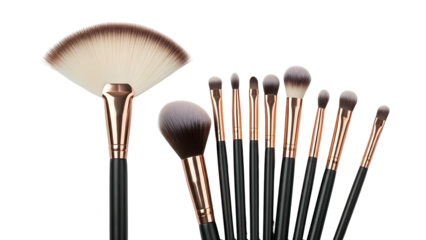 Assortment of makeup brushes, black handles, gold ferrules, against a black background