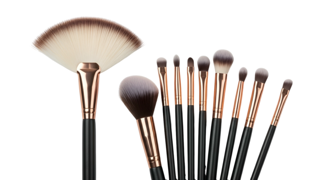 Assortment of makeup brushes, black handles, gold ferrules, against a black background