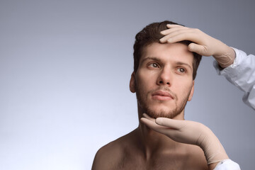Aesthetic specialist reviewing male forehead and jaw alignment. Concept of clinical training visuals, proportion mapping, anatomy lessons, and pre-procedure planning for contour work.