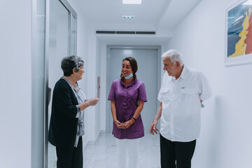 An elderly couple engages in a thoughtful discussion with their dentist about modern denture...