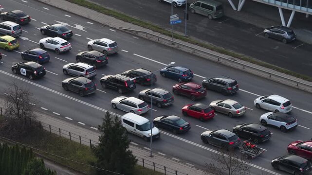 High-angle shot of slow-moving traffic on a multilane road in Vilnius, showing diverse vehicles in congestion near a divided highway with street lighting.