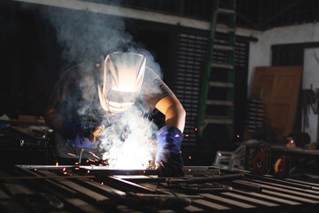 Professional welder working at the workbench. Deaf man using a welding torch in the workshop