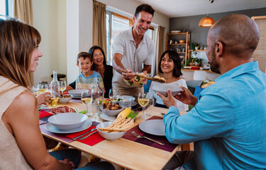 Family and friends reunion at home. Diverse family gathering enjoying dinner at home