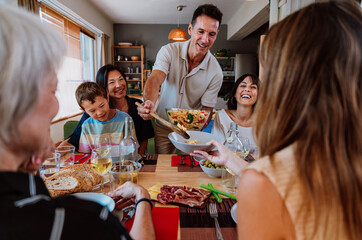 Family and friends reunion at home. Diverse family gathering enjoying dinner at home