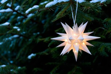 Illuminated Paper Star Ornament Hanging on Snowy Evergreen Branch - Festive Winter Decor