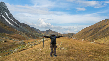 Happy hiker standing with arms raised in victory at Chaukhi Pass near Juta, Georgia. Freedom, success, and adventure in the Caucasus Mountains.