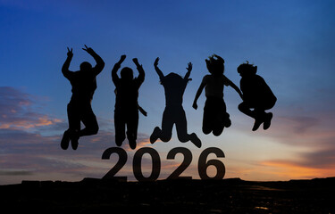Happy group of people celebrate jump for new year 2026. concept for win victory. silhouette of...