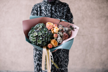 Very nice young woman holding big and beautiful bouquet of fresh hydangea, roses, carnation flowers in green and pink colors, close up cropped image