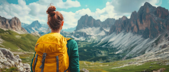 A girl with a backpack enjoys the view of mountain peaks and green valleys &mdash; an excellent backdrop for travel websites and active holiday advertising.