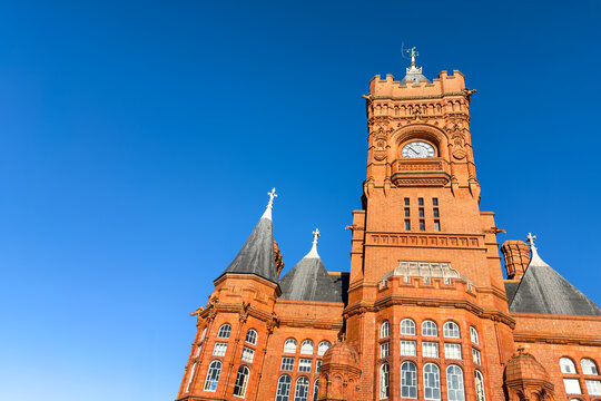 Detail of the Victorian Pierhead Building in Cardiff Bay. An iconic red brick Gothic revival building, known as the Welsh Big Ben, against a clear blue sky. Constructed in 1897.
