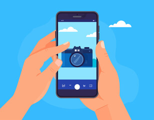 Hands holding a smartphone displaying a camera icon against a sky background, suggesting photography or mobile technology.