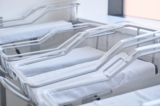 Empty hospital cribs arranged neatly in a bright nursery during the day