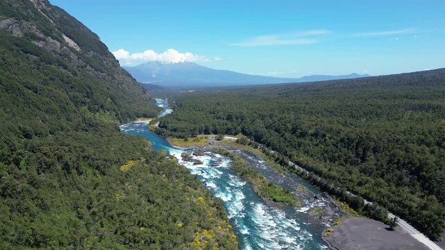 Puerto Varas, Chile: Tilt up aerial drone footage of Petrohue river near Puerto Varas in the Lake District of Chile surrounded by forest with Calbuco volcano in the background