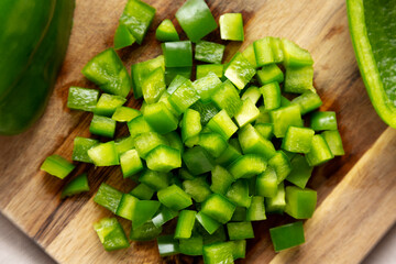 Organic Chopped Green Bell Peppers arranged on a Cutting Board, top view. Close-up.