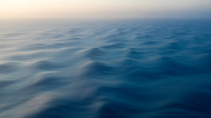 Gentle ocean waves under a hazy sky at sunrise or sunset water ripples