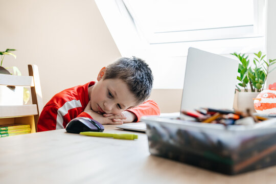 Boy feeling bored studying online with laptop