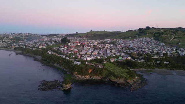 Chiloe Island, Chile: Dramatic aerial footage of sunset over Ancud residential areas, town in Chiloe Island in Lake District of Chile. Taken orbit motion