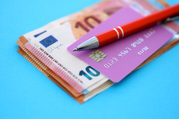 Credit card and pen with euro currency money bills banknotes on light blue background. Business,...