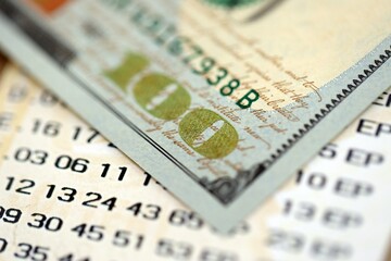 Lottery ticket and one hundred US dollar bill close up. Concept of gambling addiction and lottery