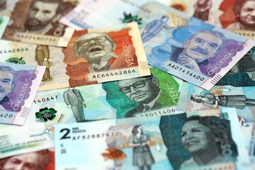 Colombian pesos money bills banknotes lies in big pile on table close up. Concept of finances and...