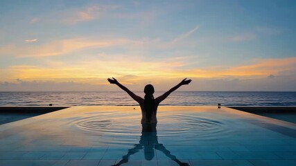 Sequence of a female silhouette raising her arms in an infinity pool at sunset. Adult woman celebrating freedom and success on a luxury vacation with a beautiful ocean view