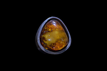 Natural amber gemstone set in a stylish silver ring displayed against a black background in a well lit setting
