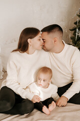 New Year, family, mom, dad, and child hugging, kissing, and playing, having fun together at home before the New Year, and congratulating each other on the New Year