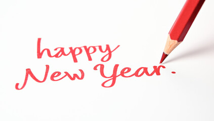 A red pencil writes happy New year on paper