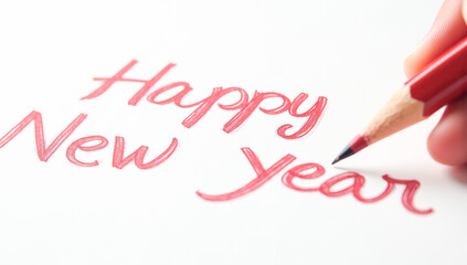 A red pencil writes happy New year on paper