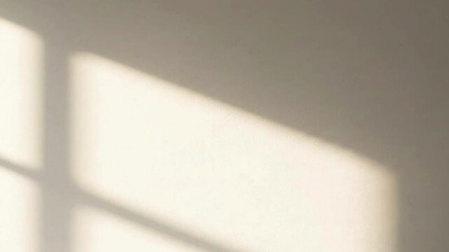 Minimalist aesthetic background with warm morning sunlight casting a window frame shadow on a neutral textured wall for product display