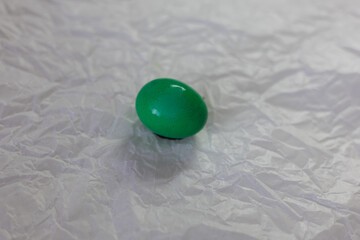 Brightly colored Easter eggs – various colors - green, yellow, red, blue – arranged on crumpled white paper. The eggs are smooth and shiny, ready for decoration or display at Easter