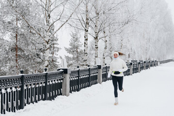 young caucasian woman running in park in winter, white sports jacket, black trousers and small waist bag on belt, active lifestyle concept, jogging in winter, sports life, copy space