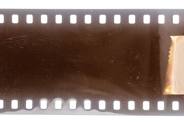 Dusty and grungy 35mm film texture or surface. Perforated scratched camera film isolated on white background.