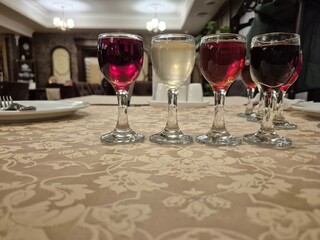 Glasses of various alcoholic beverages stand on the table.