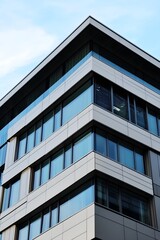 Modern office building corner with glass windows and blue sky