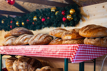 Fresh bread loaves displayed on a red-check stall beneath a festive Christmas garland at the Poznań holiday market